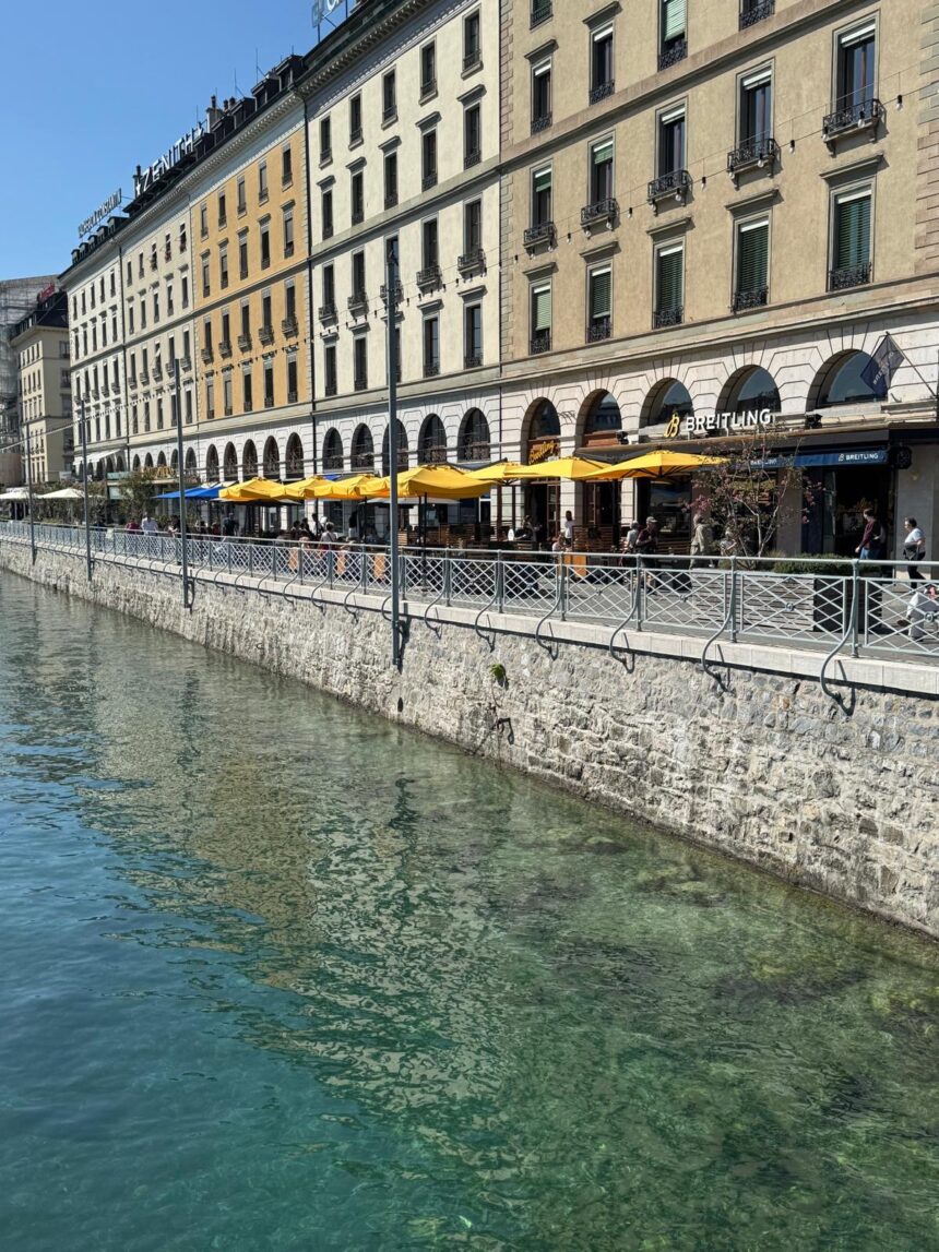 Façades et terrasses aux parasols jaunes sur un quai à Genève.